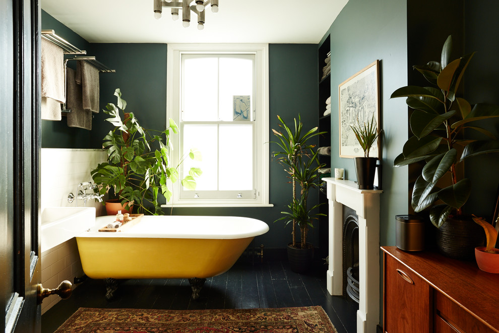 Inspiration for an eclectic ensuite bathroom with a claw-foot bath, black walls, black floors and a chimney breast.