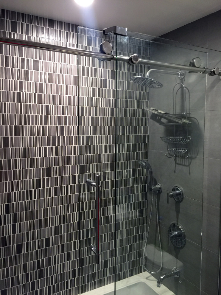 Cette image montre une salle de bain principale design de taille moyenne avec un lavabo suspendu, un plan de toilette en carrelage, une baignoire posée, un carrelage gris, des carreaux de porcelaine et un mur gris.