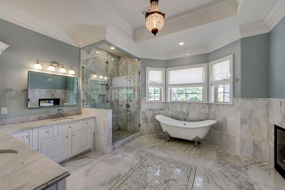 Cette photo montre une salle de bain chic avec un lavabo encastré, un placard avec porte à panneau surélevé, des portes de placard blanches, une baignoire sur pieds, une douche d'angle, un carrelage blanc et un mur gris.