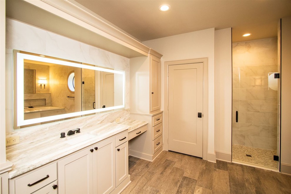 Inredning av ett klassiskt mellanstort badrum med dusch, med luckor med infälld panel, beige skåp, ett platsbyggt badkar, en dusch i en alkov, vit kakel, porslinskakel, beige väggar, mellanmörkt trägolv, ett undermonterad handfat, bänkskiva i kvarts, brunt golv och dusch med gångjärnsdörr