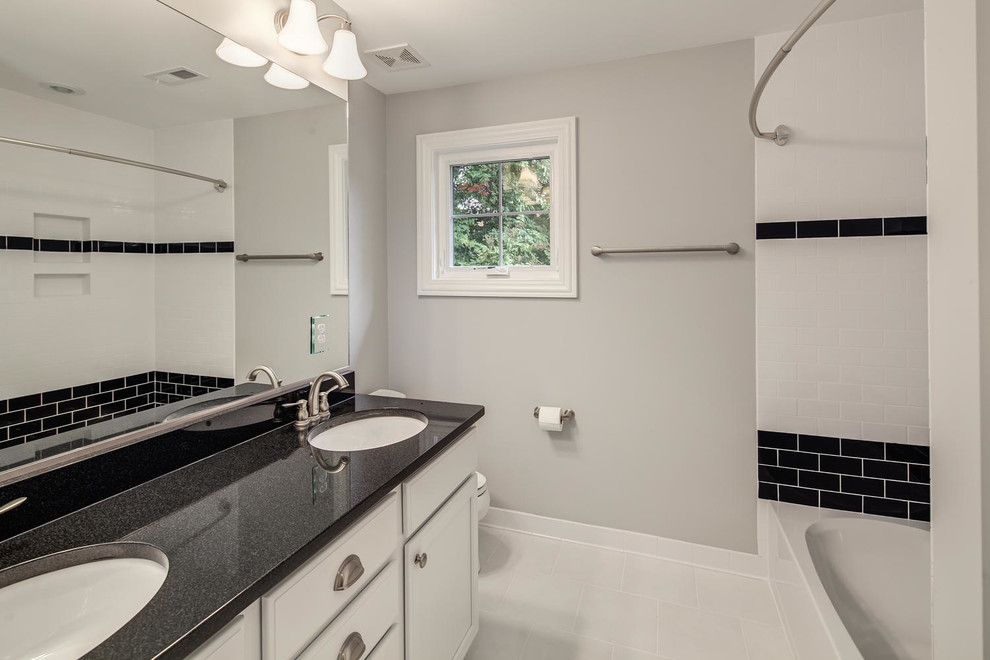 Bild på ett funkis badrum med dusch, med vita skåp, granitbänkskiva, ett badkar i en alkov, en dusch/badkar-kombination, en toalettstol med hel cisternkåpa, vit kakel, keramikplattor, grå väggar och klinkergolv i keramik