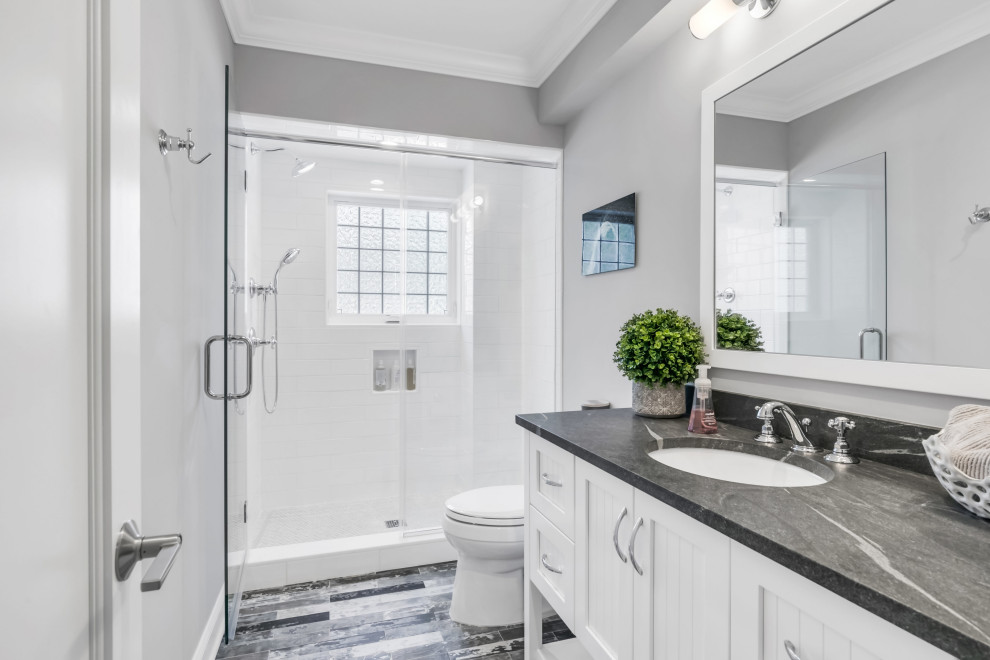 Diseño de cuarto de baño costero con armarios estilo shaker, puertas de armario blancas, ducha empotrada, baldosas y/o azulejos blancos, paredes grises, lavabo bajoencimera, suelo gris y encimeras grises