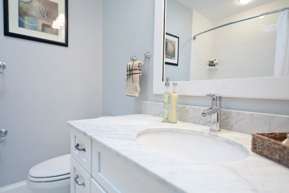 На фото: ванная комната среднего размера в классическом стиле с врезной раковиной, фасадами с утопленной филенкой, белыми фасадами, мраморной столешницей, ванной в нише, душем над ванной, унитазом-моноблоком, серыми стенами и душевой кабиной