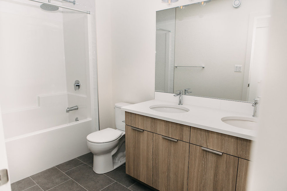 Bathroom - mid-sized modern white tile gray floor bathroom idea in Edmonton with shaker cabinets, medium tone wood cabinets, a one-piece toilet, white walls, an undermount sink and white countertops