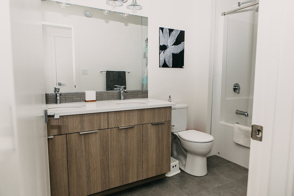 Esempio di una stanza da bagno moderna di medie dimensioni con ante in stile shaker, ante in legno chiaro, vasca ad alcova, vasca/doccia, WC monopezzo, piastrelle bianche, pareti bianche, lavabo sottopiano, pavimento grigio, doccia con tenda e top bianco