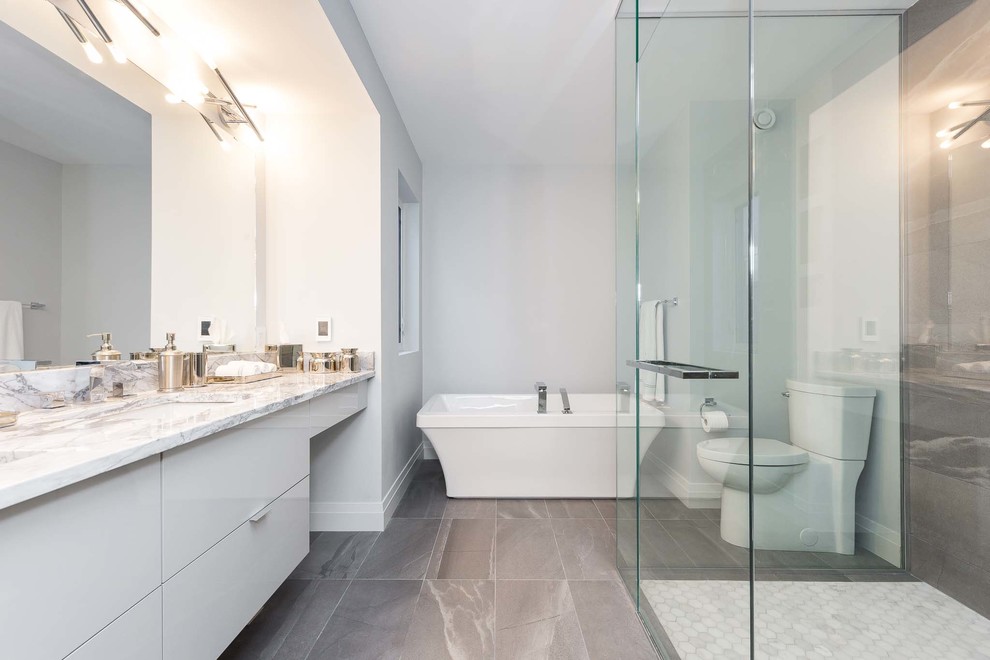 Стильный дизайн: главная ванная комната среднего размера в современном стиле с плоскими фасадами, белыми фасадами, угловым душем, унитазом-моноблоком, серой плиткой, белыми стенами, врезной раковиной и мраморной столешницей - последний тренд
