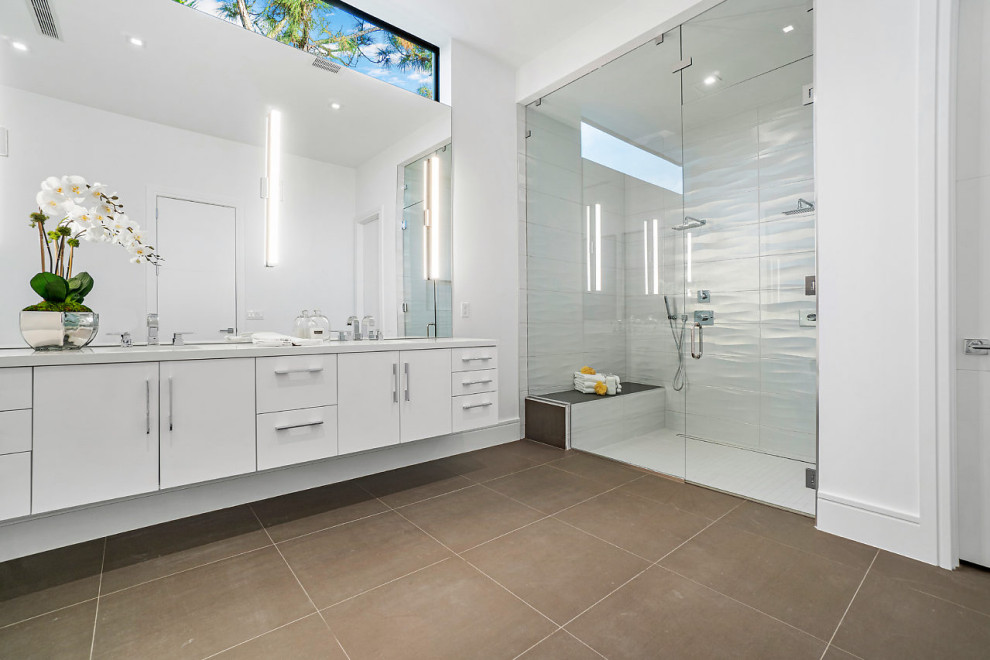 Photo of a large contemporary ensuite bathroom in Miami with flat-panel cabinets, white cabinets, an alcove shower, white walls, porcelain flooring, a submerged sink, brown floors, a hinged door and white worktops.