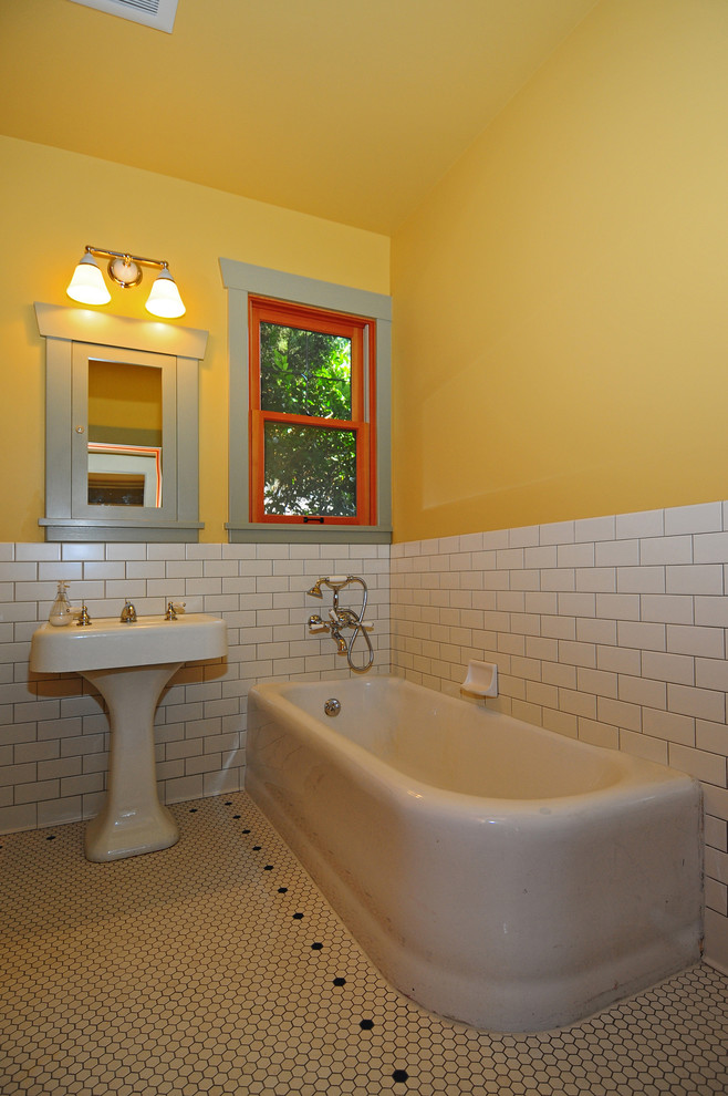 Idee per una stanza da bagno american style di medie dimensioni con lavabo a colonna, ante con riquadro incassato, ante grigie, vasca ad angolo, piastrelle bianche, piastrelle diamantate, pareti gialle e pavimento con piastrelle in ceramica
