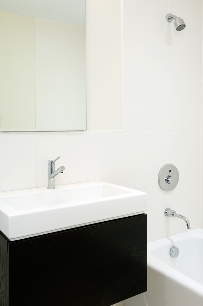 Cette image montre une petite salle d'eau design avec un lavabo suspendu, un combiné douche/baignoire, un placard à porte plane, des portes de placard noires, une baignoire en alcôve, un carrelage blanc, des carreaux de céramique, un mur blanc et une cabine de douche avec un rideau.