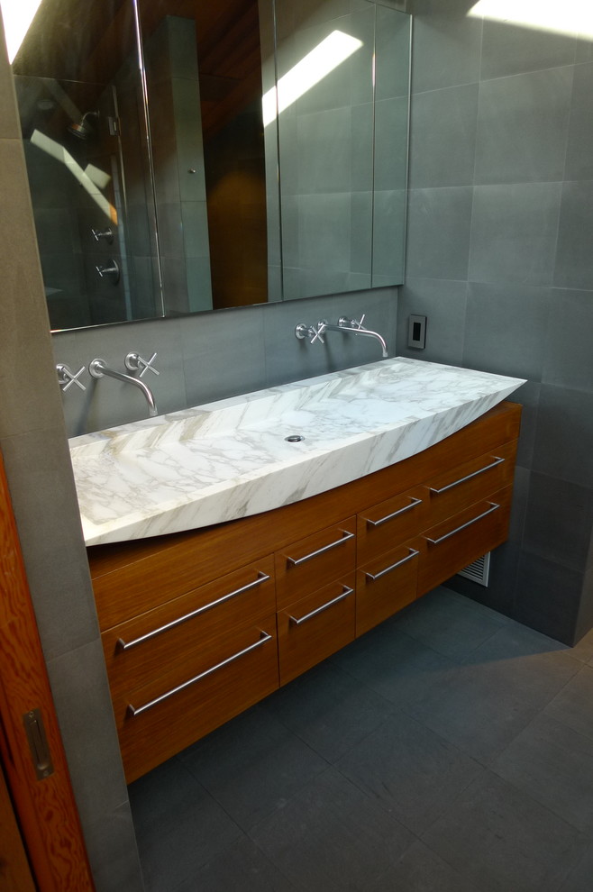 Immagine di una stanza da bagno padronale minimalista con lavabo a bacinella, consolle stile comò, ante in legno scuro, top in marmo, WC monopezzo e lastra di pietra