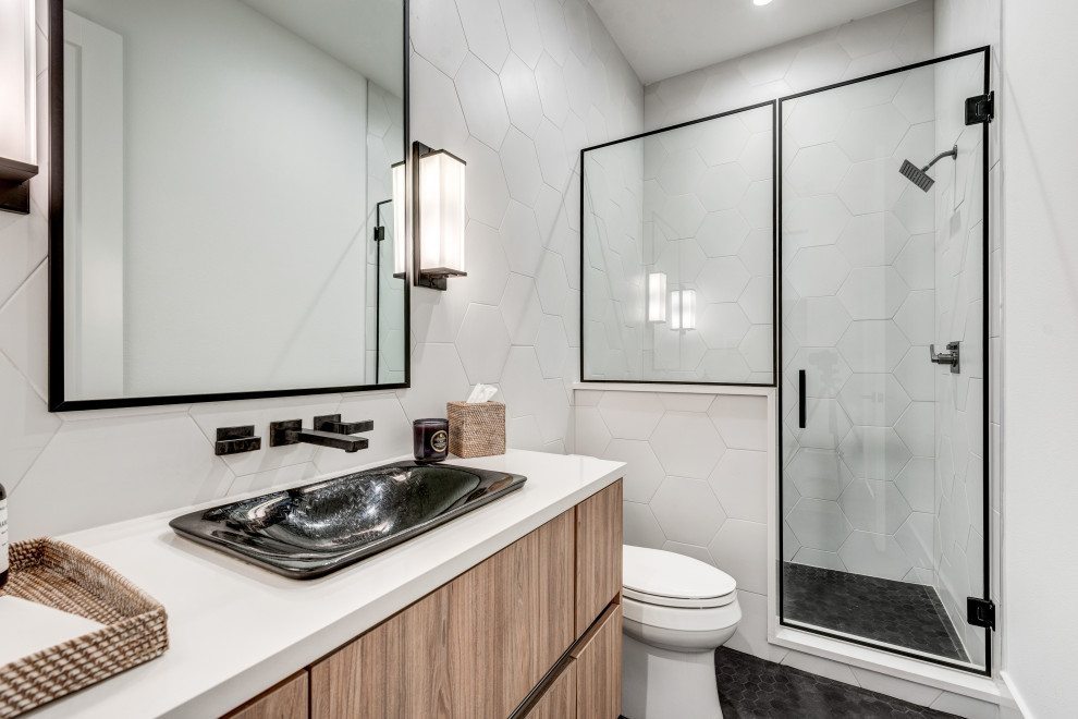 Imagen de cuarto de baño único y flotante, contemporáneo, de tamaño medio, con armarios con paneles lisos, puertas de armario de madera oscura, ducha empotrada, sanitario de dos piezas, baldosas y/o azulejos blancos, baldosas y/o azulejos de porcelana, aseo y ducha, lavabo sobreencimera, suelo negro, ducha con puerta con bisagras, encimeras blancas, paredes blancas y suelo de baldosas de cerámica