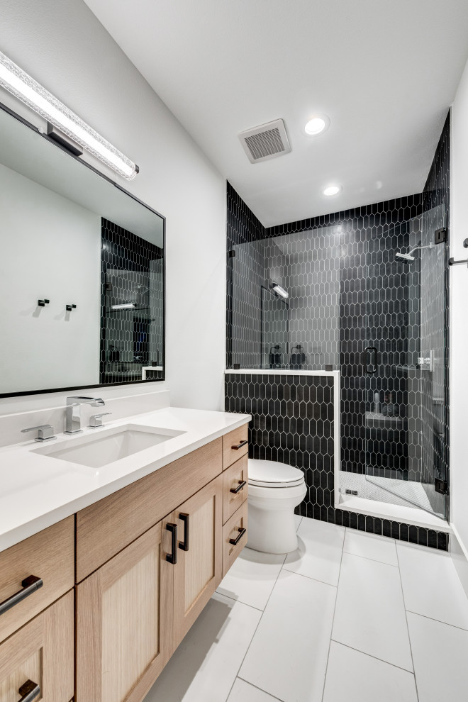 Photo of a large classic shower room bathroom in Dallas with shaker cabinets, light wood cabinets, an alcove shower, a two-piece toilet, black tiles, porcelain tiles, white walls, porcelain flooring, a submerged sink, grey floors, a hinged door, white worktops, a single sink and a floating vanity unit.