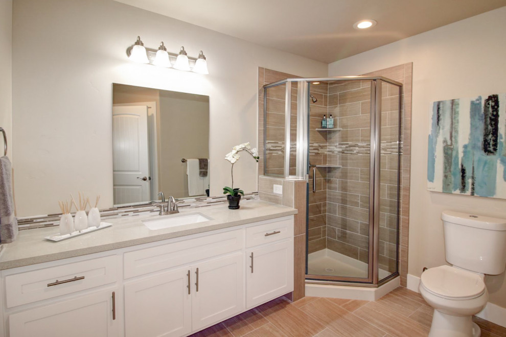 Exempel på ett mellanstort modernt beige beige badrum med dusch, med en hörndusch, beige väggar, laminatgolv, ett fristående handfat, grått golv, luckor med infälld panel, vita skåp, en jacuzzi, en toalettstol med separat cisternkåpa, flerfärgad kakel, mosaik, bänkskiva i kvarts och dusch med gångjärnsdörr