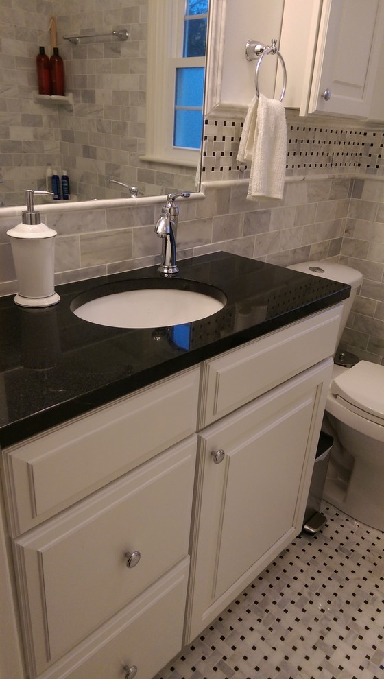 Photo of a small traditional ensuite bathroom in Philadelphia with raised-panel cabinets, white cabinets, an alcove bath, a shower/bath combination, a two-piece toilet, black and white tiles, stone tiles, white walls, marble flooring, a submerged sink and granite worktops.
