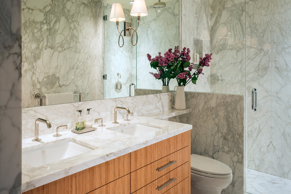 Inredning av ett modernt mellanstort en-suite badrum, med ett undermonterad handfat, släta luckor, skåp i mellenmörkt trä, marmorbänkskiva, en dusch i en alkov, en vägghängd toalettstol, vit kakel, stenkakel, vita väggar och marmorgolv