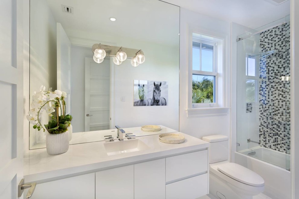 Example of a mid-sized trendy master multicolored tile and mosaic tile porcelain tile and white floor bathroom design in Other with flat-panel cabinets, white cabinets, a one-piece toilet, white walls, an integrated sink, solid surface countertops, a hinged shower door and white countertops