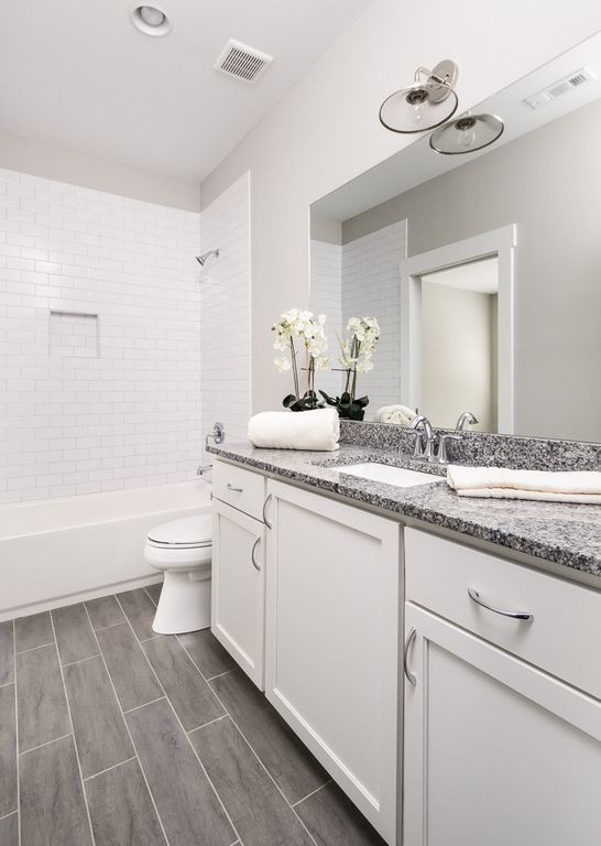 Medium sized classic shower room bathroom in Atlanta with raised-panel cabinets, white cabinets, a submerged bath, a walk-in shower, white tiles, metro tiles, white walls, limestone flooring, a submerged sink, marble worktops, grey floors, an open shower and black worktops.