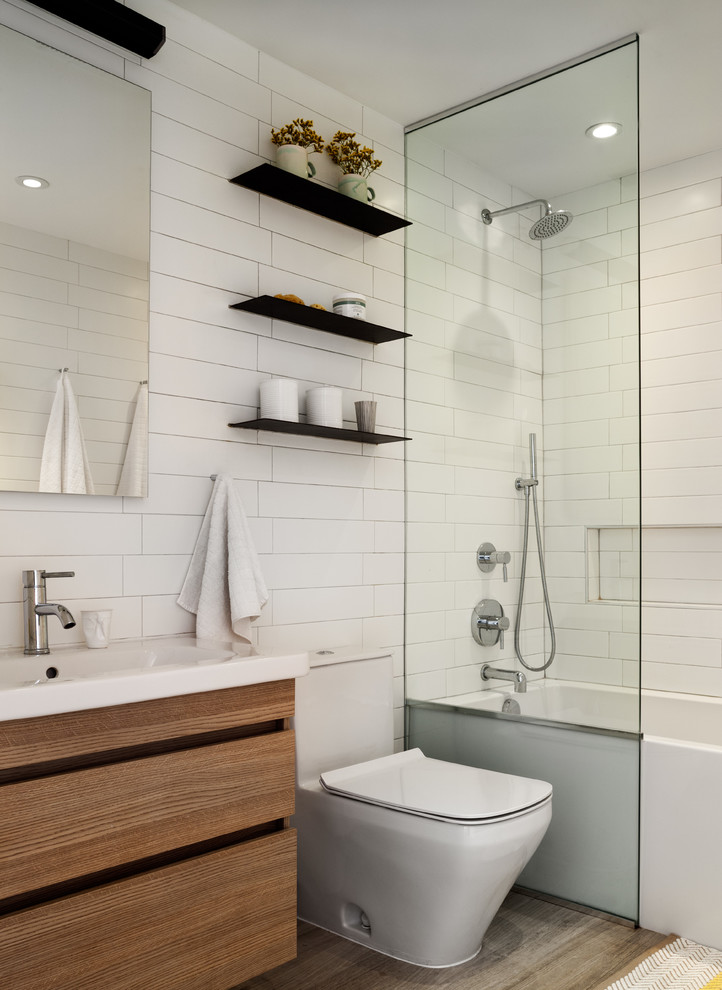 ニューヨークにあるお手頃価格の小さなコンテンポラリースタイルのおしゃれなバスルーム (浴槽なし) (アルコーブ型浴槽、シャワー付き浴槽	、一体型トイレ	、白いタイル、白い壁、オープンシャワー、中間色木目調キャビネット、コンソール型シンク、グレーの床) の写真