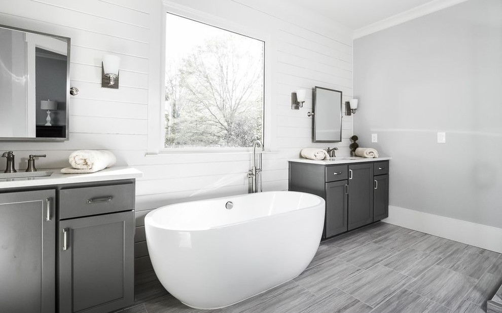 Cette image montre une grande salle de bain principale traditionnelle avec un placard avec porte à panneau surélevé, des portes de placard grises, une baignoire encastrée, une douche d'angle, un carrelage blanc, des carreaux de céramique, un mur blanc, un lavabo encastré, un plan de toilette en marbre, un plan de toilette blanc, un sol en linoléum et un sol gris.