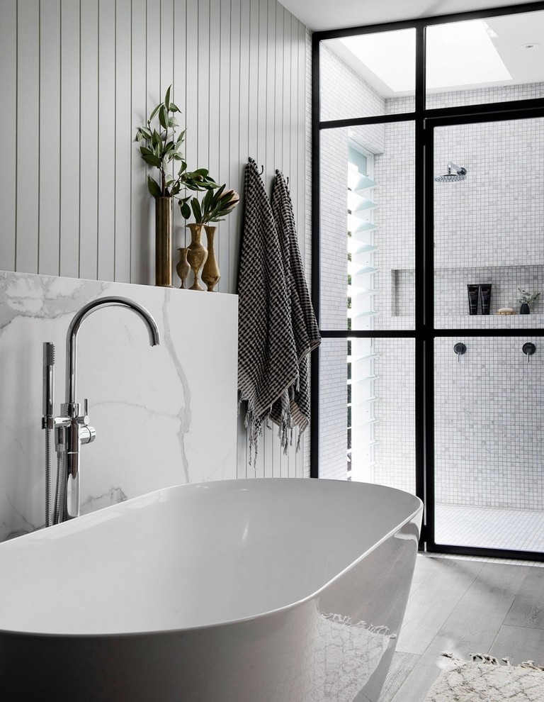 Diseño de cuarto de baño minimalista con bañera exenta, baldosas y/o azulejos blancos, baldosas y/o azulejos de porcelana, paredes blancas, suelo de madera oscura, suelo marrón, ducha abierta y encimeras blancas