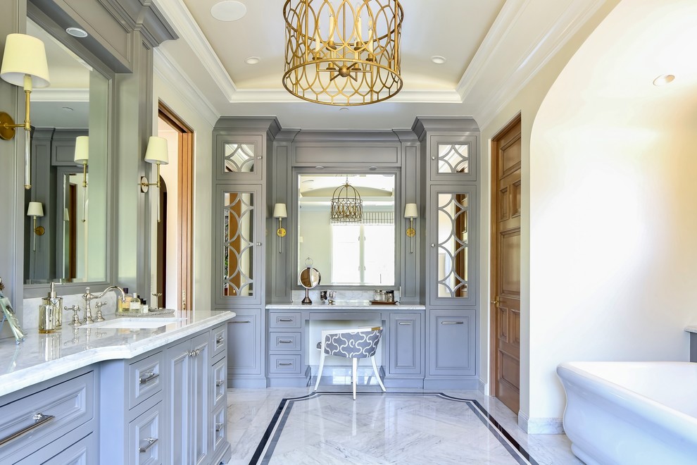 Источник вдохновения для домашнего уюта: огромная главная ванная комната в стиле неоклассика (современная классика) с фасадами с утопленной филенкой, синими фасадами, отдельно стоящей ванной, мраморным полом, врезной раковиной, мраморной столешницей, белой столешницей, бежевыми стенами, разноцветным полом и зеркалом с подсветкой
