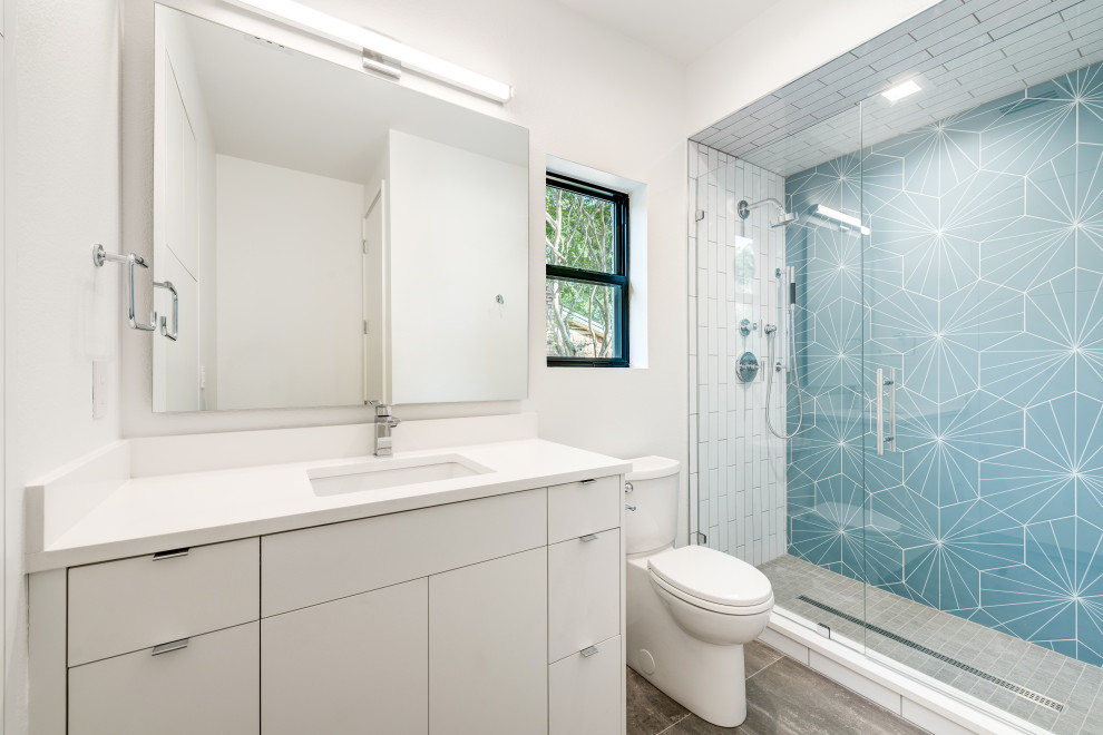 Свежая идея для дизайна: большая ванная комната в современном стиле с плоскими фасадами, белыми фасадами, угловым душем, раздельным унитазом, синей плиткой, керамогранитной плиткой, белыми стенами, полом из керамогранита, душевой кабиной, врезной раковиной, столешницей из искусственного кварца, серым полом, душем с распашными дверями, белой столешницей, тумбой под одну раковину и подвесной тумбой - отличное фото интерьера