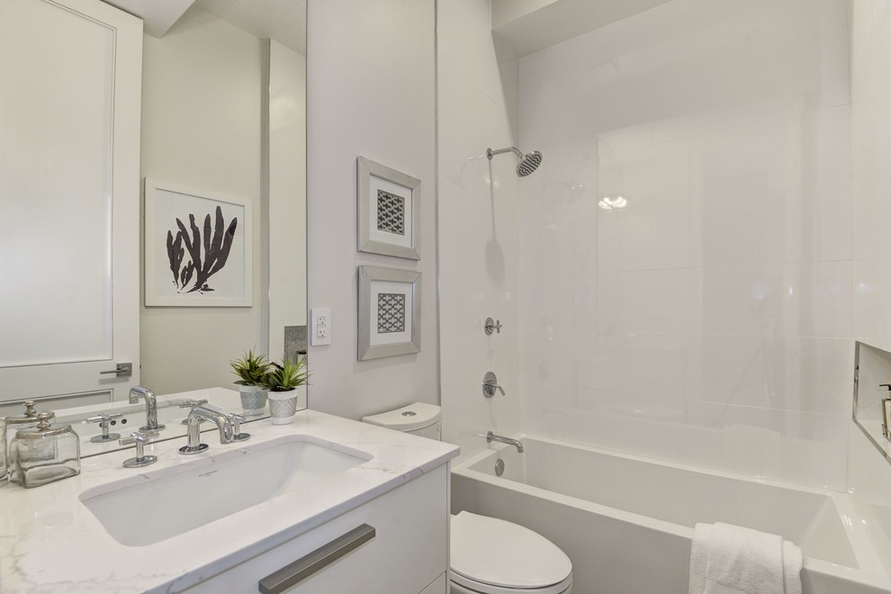 Design ideas for a small contemporary bathroom in DC Metro with flat-panel cabinets, white cabinets, a shower/bath combination, white tiles, white walls and engineered stone worktops.