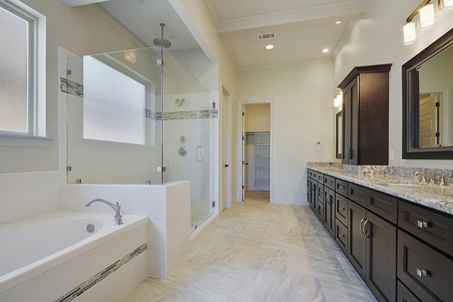 Photo of a large classic ensuite bathroom in New Orleans with a submerged sink, raised-panel cabinets, dark wood cabinets, granite worktops, a freestanding bath, a double shower, a one-piece toilet, beige tiles, ceramic tiles, white walls and ceramic flooring.
