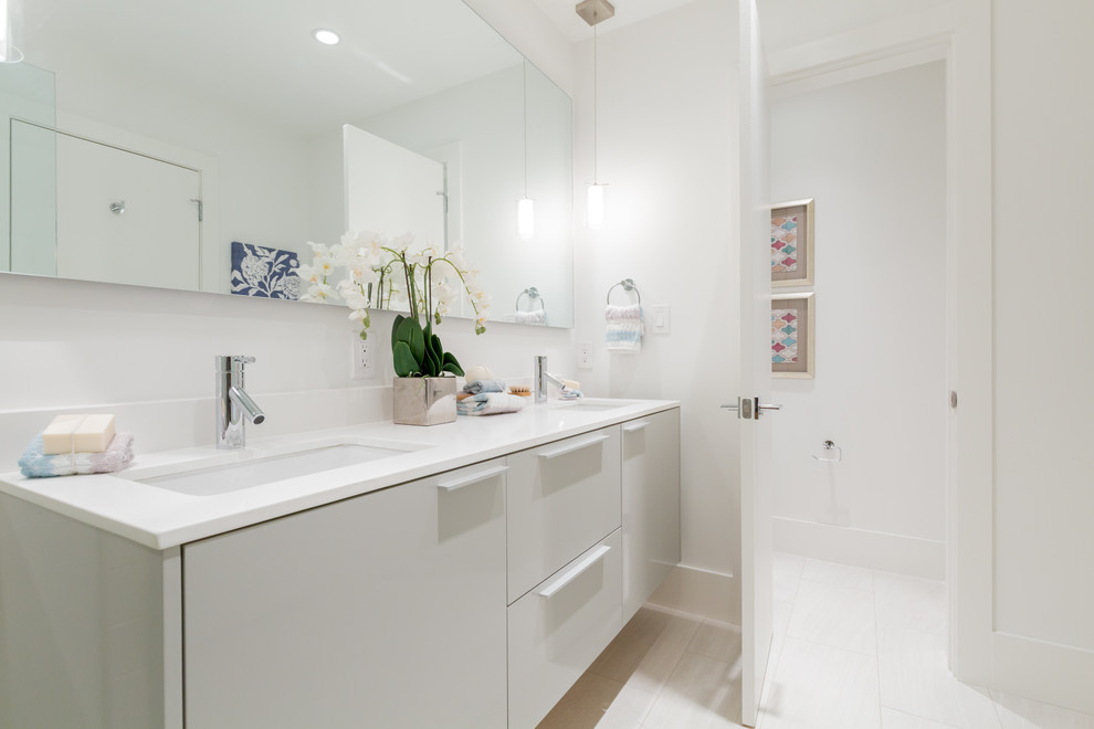 Aménagement d'une salle de bain contemporaine avec un lavabo encastré, un placard à porte plane et des portes de placard blanches.