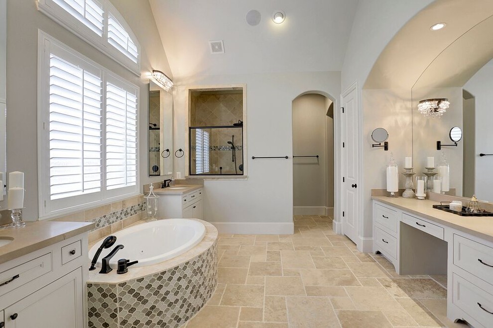 На фото: большая главная ванная комната в классическом стиле с фасадами в стиле шейкер, белыми фасадами, накладной ванной, серой плиткой, плиткой из травертина, серыми стенами, полом из травертина, врезной раковиной и черным полом с