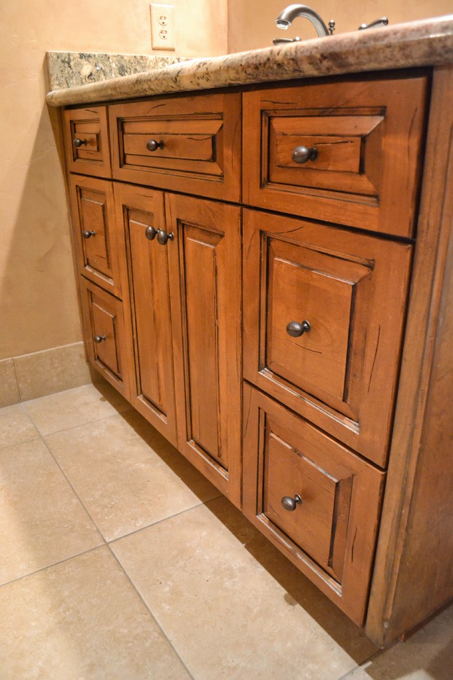 Foto de cuarto de baño tradicional de tamaño medio con armarios con paneles con relieve, puertas de armario de madera oscura, suelo de baldosas de porcelana, aseo y ducha, encimera de granito y suelo beige