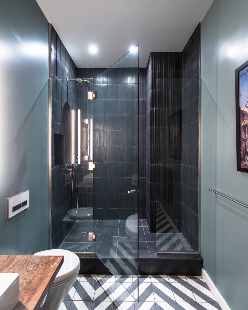 ニューヨークにある高級な中くらいなインダストリアルスタイルのおしゃれなバスルーム (浴槽なし) (ベッセル式洗面器、木製洗面台、アルコーブ型シャワー、壁掛け式トイレ、黒いタイル、スレートタイル、青い壁、セラミックタイルの床) の写真