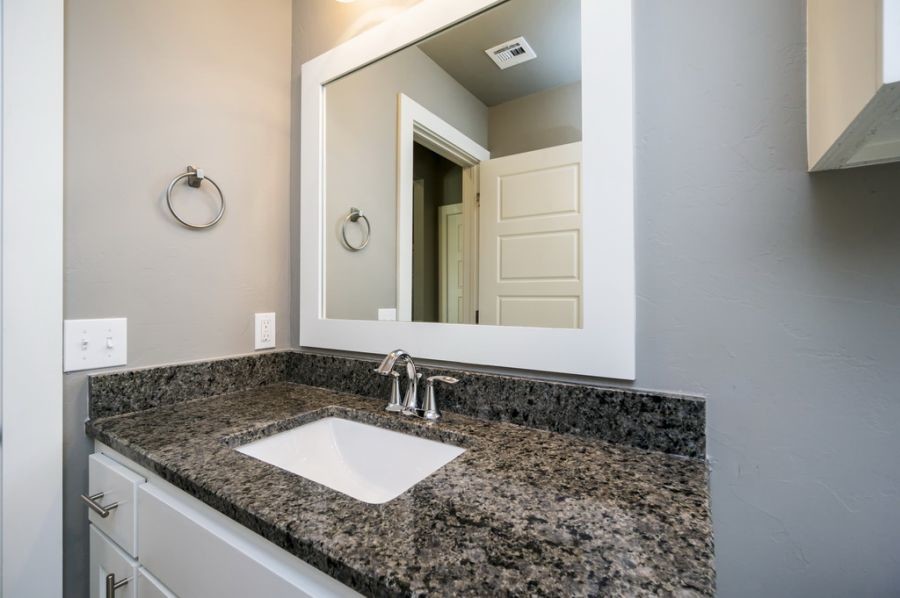 Bild på ett funkis badrum, med skåp i shakerstil, vita skåp, ett badkar i en alkov, en dusch/badkar-kombination, en toalettstol med separat cisternkåpa, grå kakel, keramikplattor, grå väggar, klinkergolv i keramik, ett undermonterad handfat och granitbänkskiva