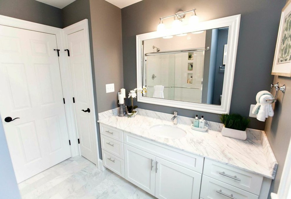 Imagen de cuarto de baño clásico con lavabo bajoencimera, armarios con paneles empotrados, puertas de armario blancas, paredes grises y suelo de mármol