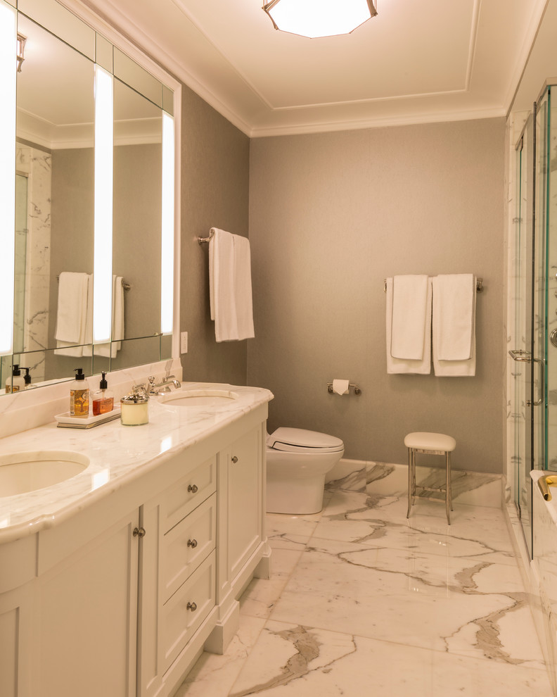 Photo of a large traditional shower room bathroom in New York with shaker cabinets, white cabinets, an alcove shower, white tiles, stone tiles, grey walls, marble flooring, a submerged sink and marble worktops.