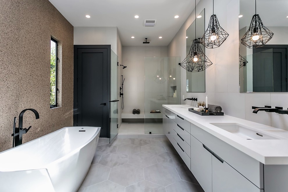 This is an example of a contemporary ensuite bathroom in Los Angeles with flat-panel cabinets, grey cabinets, a freestanding bath, a built-in shower, a submerged sink, grey floors and a hinged door.