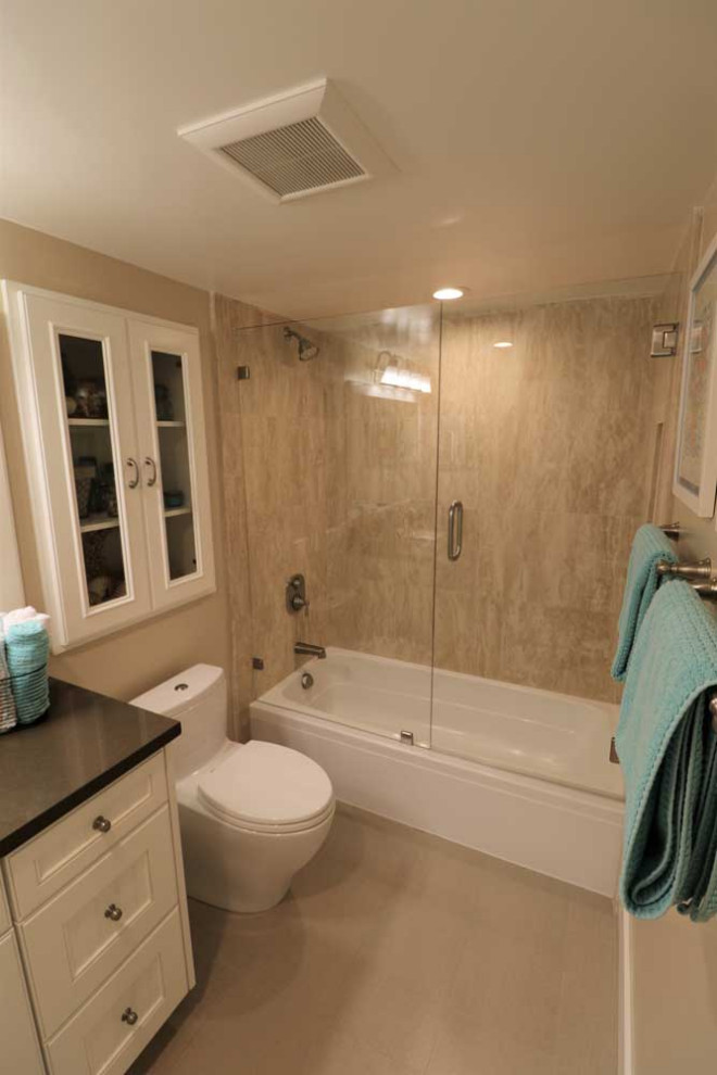 Inspiration for a medium sized traditional ensuite wet room bathroom in Orange County with open cabinets, white cabinets, a built-in bath, a one-piece toilet, grey tiles, marble tiles, grey walls, ceramic flooring, a console sink, granite worktops, grey floors, a sliding door and black worktops.
