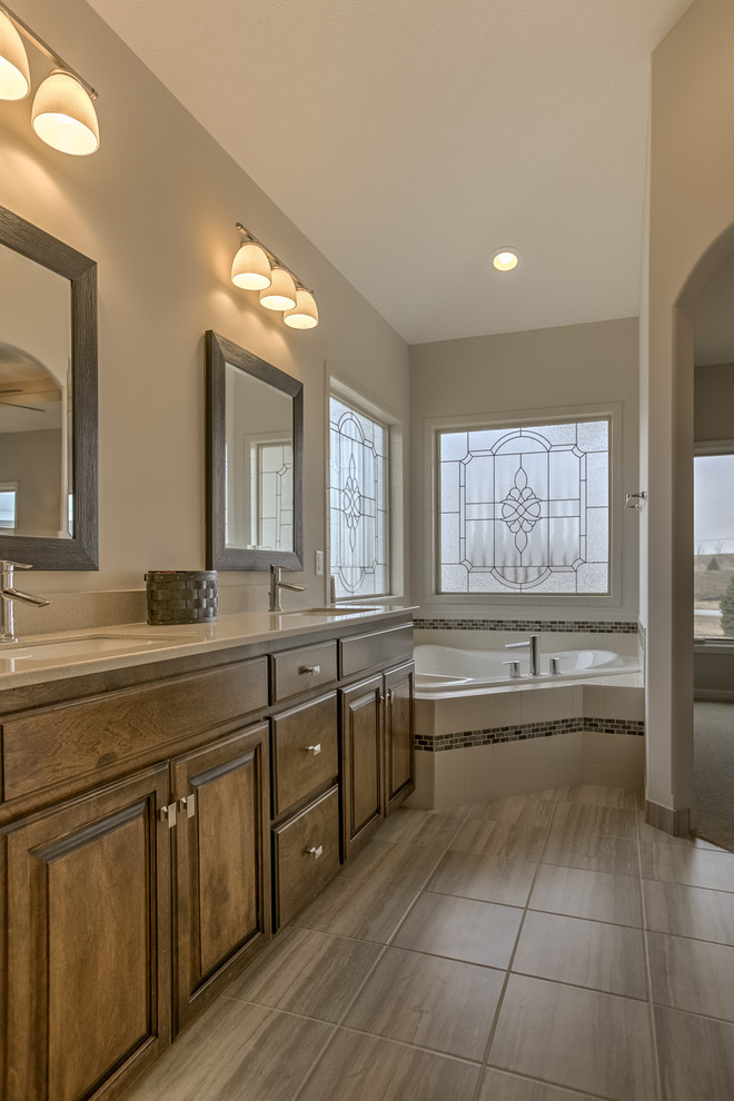 Inspiration for a mid-sized modern master multicolored tile and ceramic tile vinyl floor and beige floor corner bathtub remodel in Omaha with raised-panel cabinets, medium tone wood cabinets, beige walls, an undermount sink and quartz countertops