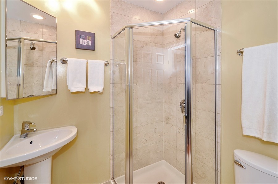 Small traditional shower room bathroom in Chicago with a pedestal sink, a corner shower, beige tiles, stone tiles and yellow walls.