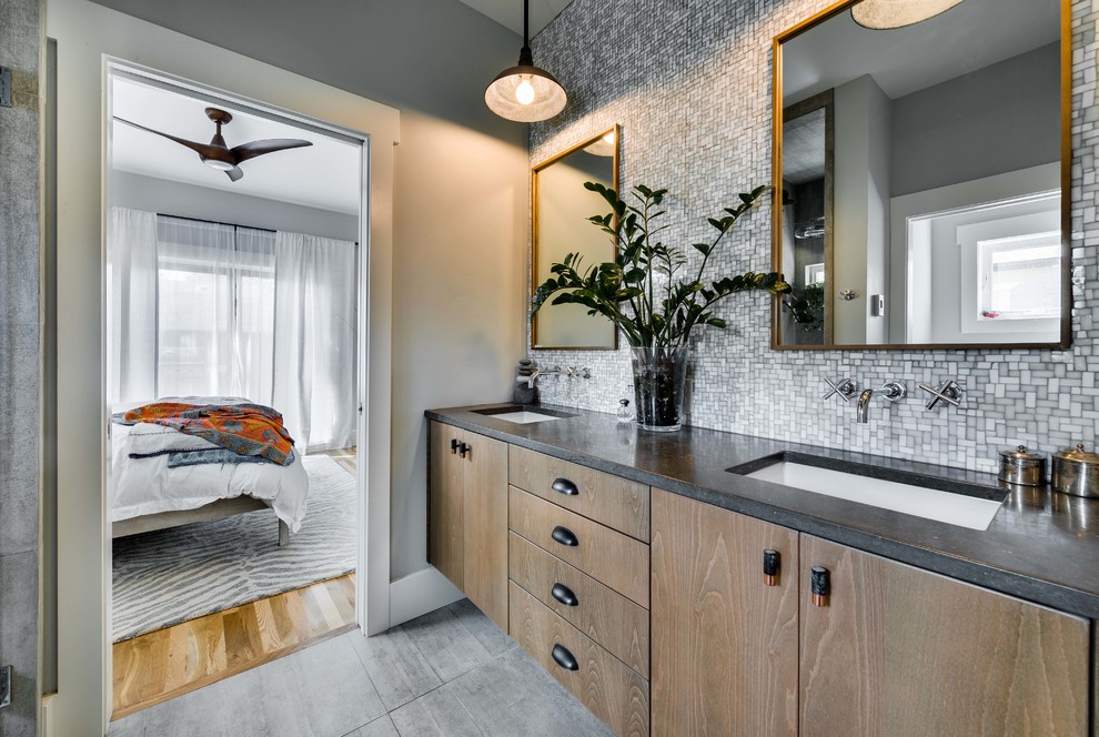 Inspiration for a mid-sized coastal master gray tile and cement tile ceramic tile corner shower remodel in Boise with flat-panel cabinets, medium tone wood cabinets, a one-piece toilet, gray walls, an integrated sink and limestone countertops