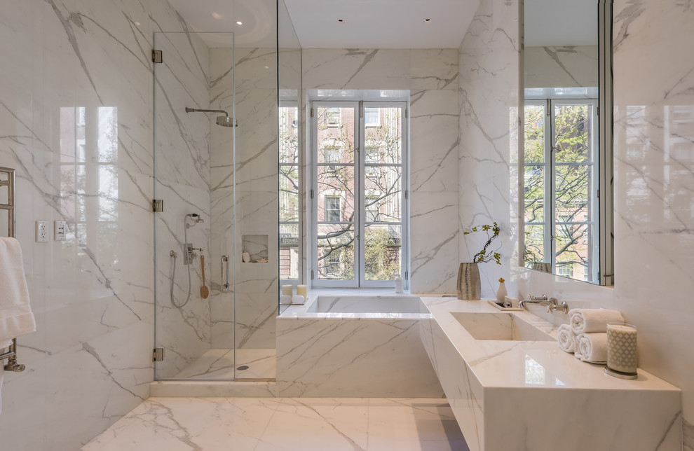 Réalisation d'une salle de bain design avec un plan de toilette en marbre, une baignoire d'angle, une douche d'angle et un sol en marbre.