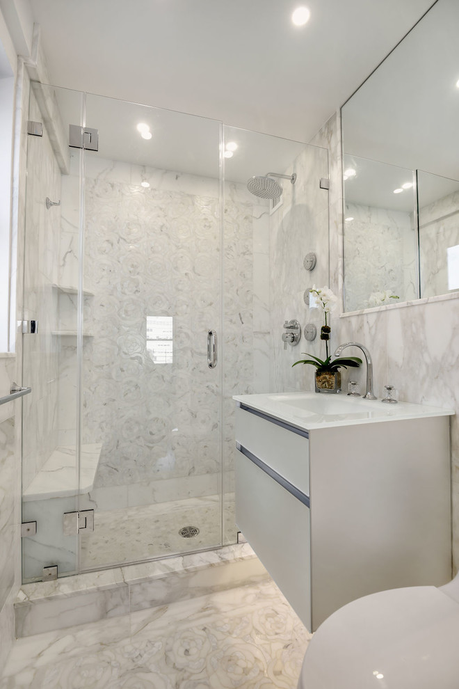 Пример оригинального дизайна: маленькая главная ванная комната в стиле неоклассика (современная классика) с стеклянными фасадами, серыми фасадами, душем в нише, унитазом-моноблоком, серой плиткой, мраморной плиткой, серыми стенами, мраморным полом, монолитной раковиной, стеклянной столешницей, серым полом, душем с распашными дверями и белой столешницей для на участке и в саду