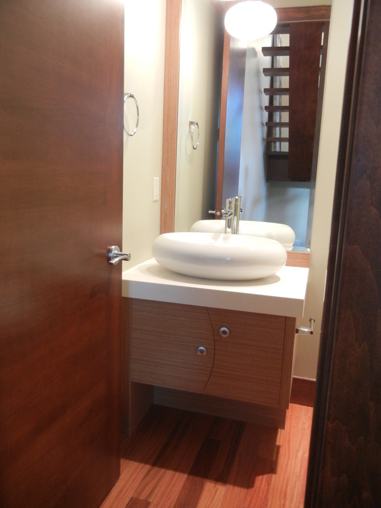 Cette image montre une petite salle d'eau design en bois clair avec un placard à porte plane, un sol en bois brun, un lavabo de ferme et un plan de toilette en quartz.