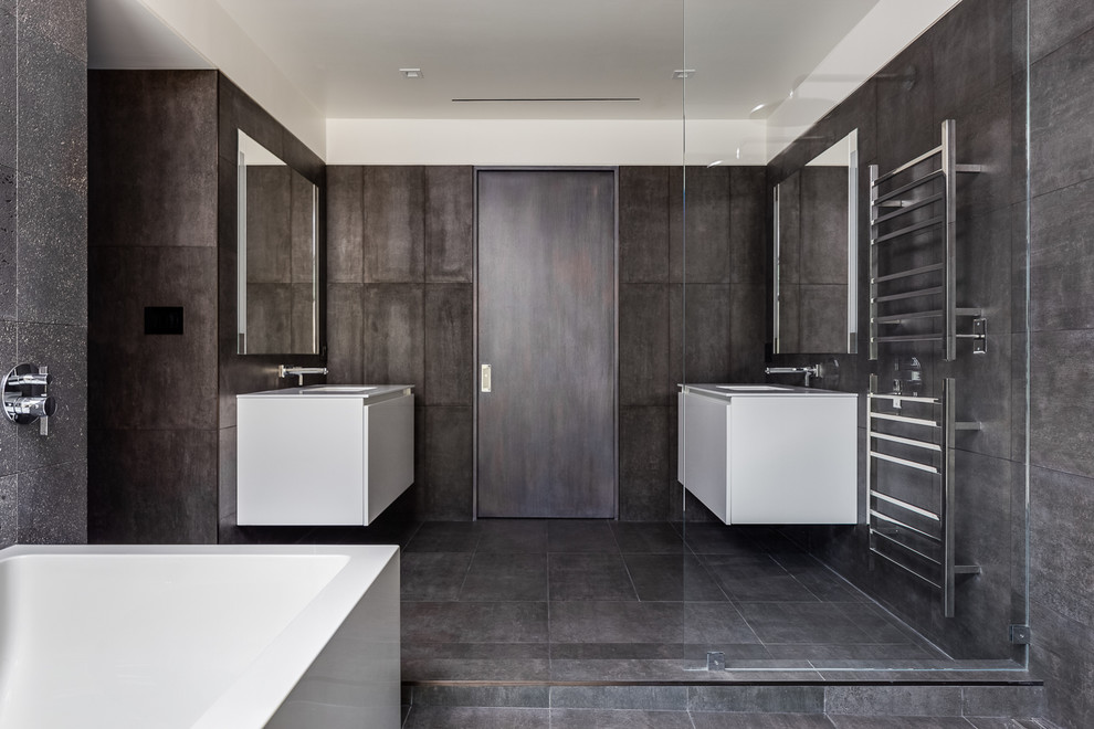 Стильный дизайн: большая главная ванная комната в современном стиле с плоскими фасадами, угловой ванной, открытым душем, черной плиткой, керамогранитной плиткой, черными стенами, полом из керамогранита и монолитной раковиной - последний тренд