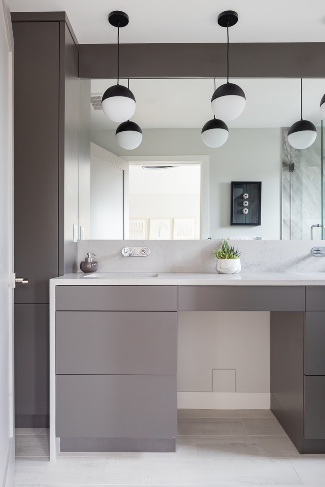 Inredning av ett modernt litet vit vitt en-suite badrum, med släta luckor, grå skåp, en dusch i en alkov, grå kakel, stenkakel, grå väggar, klinkergolv i porslin, ett undermonterad handfat, bänkskiva i kvarts, dusch med gångjärnsdörr och grått golv