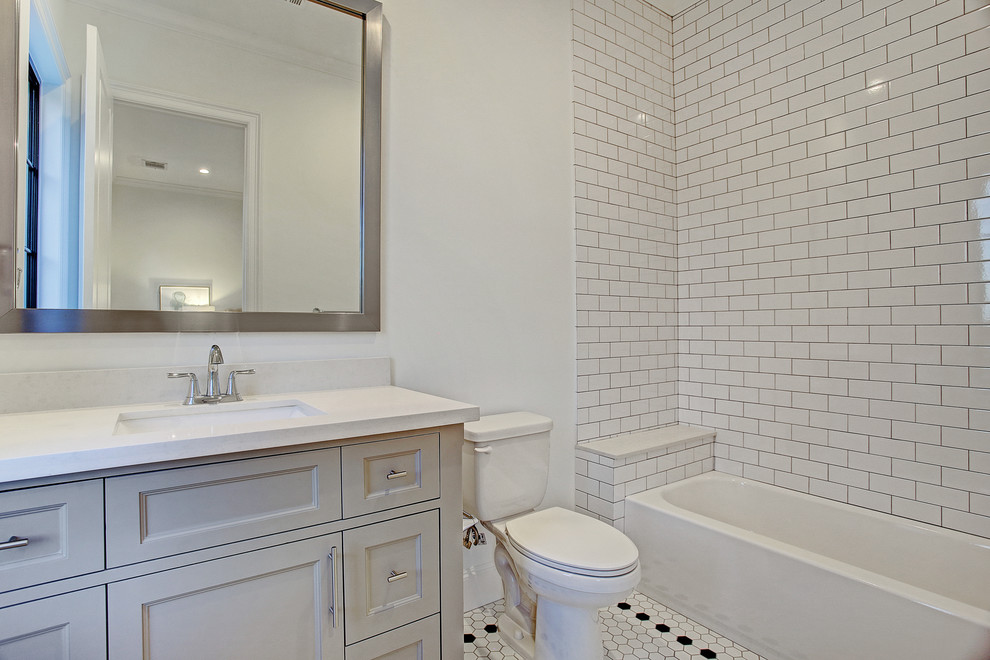 Inredning av ett klassiskt mellanstort vit vitt badrum med dusch, med möbel-liknande, grå skåp, ett badkar i en alkov, en dusch/badkar-kombination, en toalettstol med separat cisternkåpa, vit kakel, keramikplattor, vita väggar, klinkergolv i porslin, ett undermonterad handfat, bänkskiva i kvarts och vitt golv