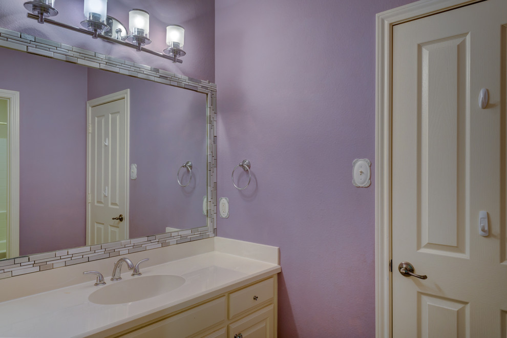 Inspiration pour une salle de bain traditionnelle de taille moyenne avec un placard avec porte à panneau surélevé, des portes de placard blanches, un mur violet, un sol en carrelage de céramique, un lavabo intégré et un plan de toilette en surface solide.