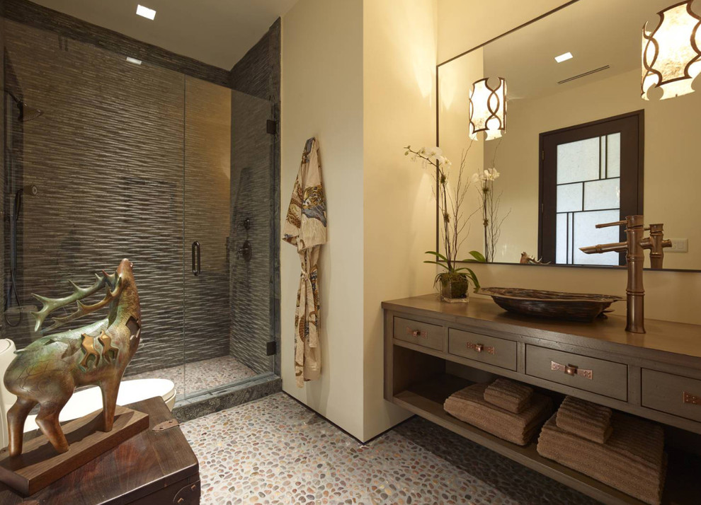 Alcove shower - mid-sized zen 3/4 gray tile pebble tile floor and multicolored floor alcove shower idea in Other with flat-panel cabinets, dark wood cabinets, a two-piece toilet, beige walls, a vessel sink, wood countertops, a hinged shower door and brown countertops