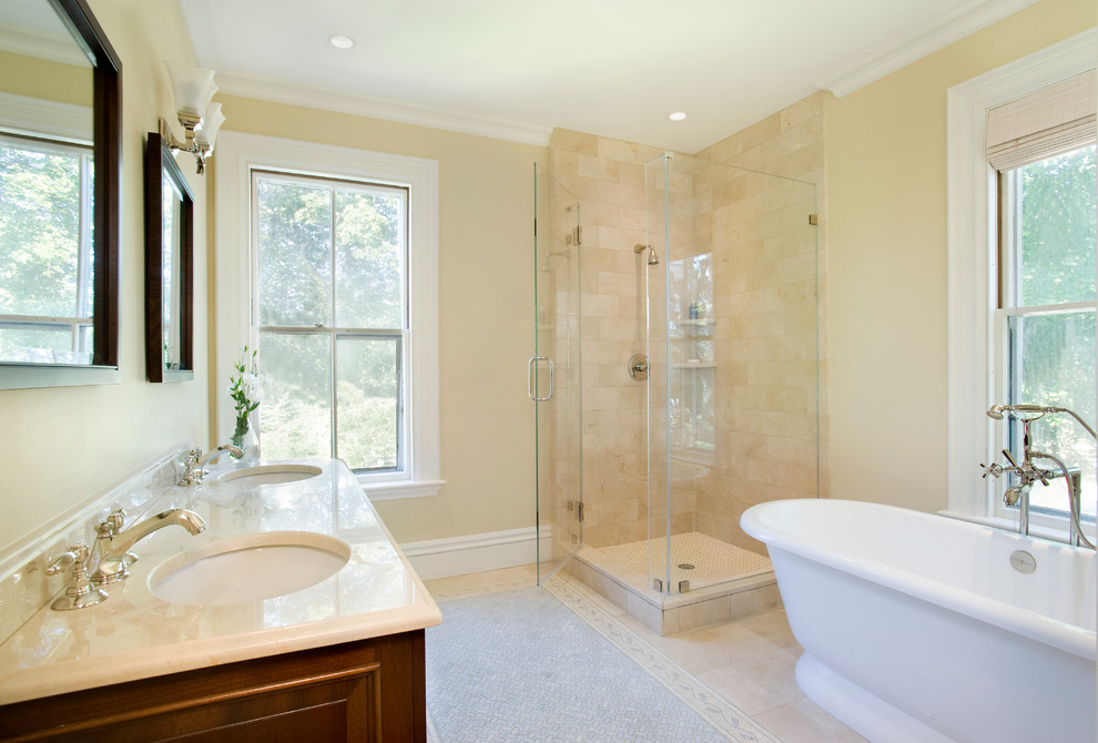 Cette photo montre une salle de bain principale chic en bois brun de taille moyenne avec un lavabo encastré, une baignoire indépendante, une douche d'angle, un plan de toilette en surface solide, un carrelage beige, un mur beige et un sol en marbre.