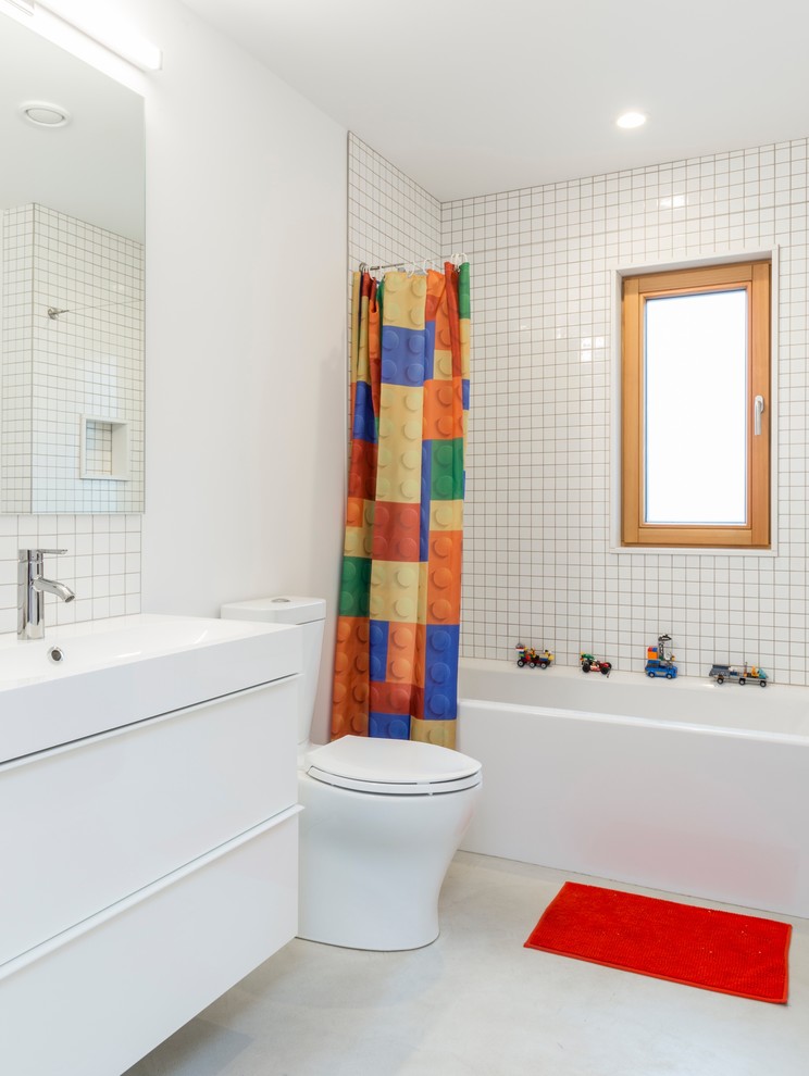 Modernes Duschbad mit flächenbündigen Schrankfronten, weißen Schränken, Badewanne in Nische, Duschbadewanne, Toilette mit Aufsatzspülkasten, weißen Fliesen, weißer Wandfarbe, Betonboden, Waschtischkonsole, grauem Boden und Duschvorhang-Duschabtrennung in Portland